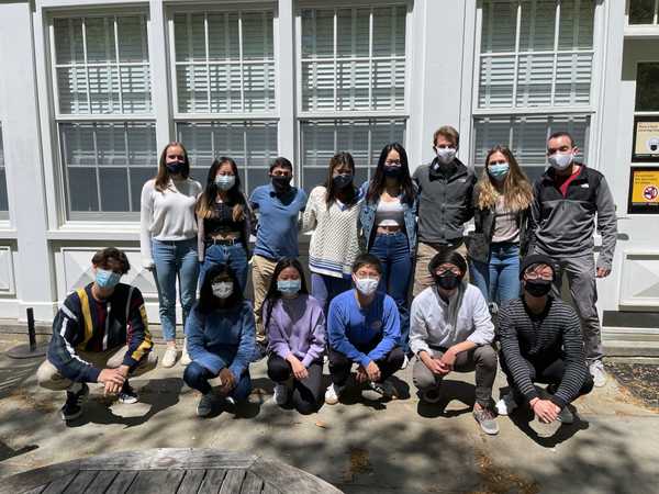 Group of students posing for picture while wearing masks outside